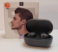 Photo showing Soundpeats H1 earbuds in open charging case with product box in background