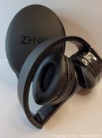 Black Zihnio wireless headphones resting against a black hard shell carrying case with Zihnio branding, white background