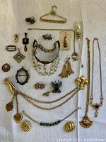 Photo showing all 22 vintage costume jewelry pieces displayed on white fabric, including necklaces, earrings, brooches, pins, and bracelets.