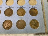 Close-up of Indian Head pennies dated 1900, 1907, and a Flying Eagle penny dated 1858, showing detailed design and wear.