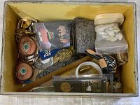 Top-down view of box showing the novelty glasses, brooch, VHS tape and more.