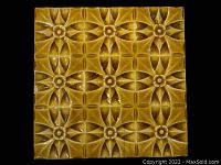 Yellow glazed ceramic tile front view showing repeating floral and geometric relief pattern on a 6x6 inch square ceramic tile.