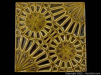 Top side of square glazed ceramic tile showing embossed geometric starburst design in olive green glaze.