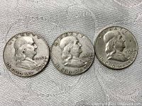 Obverse view of three Franklin half dollar coins showing Benjamin Franklin and dates 1952, 1963, 1958.