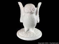 Front view of milk glass owl toothpick holder showing detailed face, wings raised and standing on round base.