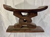 Side angled view of the carved wooden bench showing the curved top seat and interlinking knot base.
