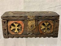 Front view of carved wooden box showing metal latch, carved quatrefoil shapes painted yellow with red border,and overall front design.