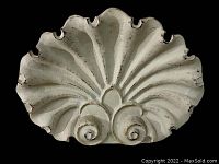 Close-up photo of vintage cast iron scallop shell doorstop showing detailed ribbed and curled shell design, with visible paint wear.