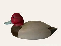 Side view of vintage wooden duck decoy showing red head, light blue bill, grey body, dark brown neck, and small crack on back.