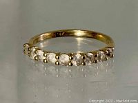 Close-up photo of gold ring with clear crystals set in a row on front.