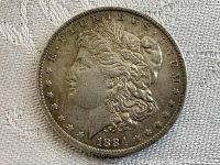 Obverse side of the 1884 Morgan Silver Dollar, highlighting the left-facing profile of Liberty and inscriptions.