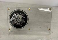 Top view of signed Buffalo Sabers hockey puck inside clear acrylic display case with gold screws.