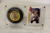 Photo of the signed hockey puck and signed Joe Thornton rookie card displayed side by side in a clear acrylic case.