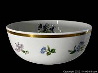 White ceramic bowl front view showing floral pattern and gold rim on exterior.