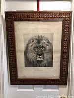 Full view of large wooden picture frame with floral carved border holding the lion engraving.