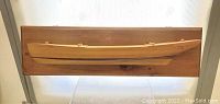 Full front view of the mounted wooden half hull ship model on a dark wooden plaque