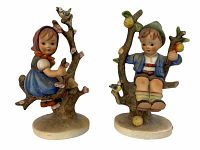 Front view of pair of Hummel figurines, boy and girl sitting in apple trees with small birds and apples.