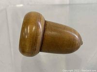 Side view of the wooden acorn shaped medicine holder showing smooth surface and shape.