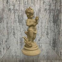 Front view of the porcelain child figurine holding a flower, showing detailed facial features, hair, and base with a small flower basket.