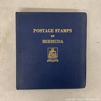Blue binder with gold embossed text and Bermuda coat of arms on the front cover indicating the title 'POSTAGE STAMPS OF BERMUDA'