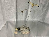 Overall view of the small seagull sculpture showing three birds on rods and one perched on the rock base.