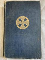 Front cover of antique book with a blue cloth hardcover and gold embossed circular cross symbol.