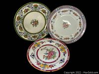 Trio of antique Mintons dinner plates arranged overlapping on a dark surface, showing their decorated fronts.