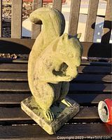 Front angled view of the vintage concrete squirrel garden statue showing details of the head, tail, and nut.