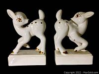 Front and side view of both white ceramic deer bookends with brown and gold detailing at a black background.