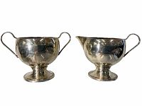 Front view of the sterling creamer and sugar dish side by side, showing handles and shape.