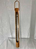 Front view of a vertical wooden framed thermometer marked Made in USA with Fahrenheit scale visible from -40 to 120 and a metal hanging loop.