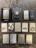 Full set of 12 Zippo lighters and one black leather Zippo case arranged on granite surface.