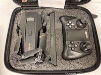 Folded black Richie 4D-V4 quadcopter with yellow accents, and 4RC branded black remote control inside protective foam case.