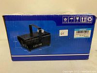 Front side of the Agptek LED-500 smoke machine box showing product image, dimensions (11.5cm x 12cm x 24cm), and handling icons.