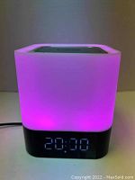 Photo showing the portable LED lamp Bluetooth speaker with digital clock display lit in purple light.