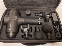 Top-down view of the Erpeo massage gun with six massage head attachments and power adapter neatly arranged in molded foam compartments inside the zippered case.
