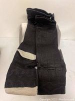 Photo showing pair of black heated socks with white accents on toe and heel, displayed upright.