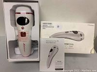 Unboxed IPL hair removal device, charger, instruction manual, and product box visible on a gray surface.