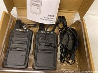 Two Retevis RT19 two way radios, user manual, and charging cable with adapter in original packaging box.