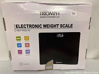 Photo of the box of a Triomph electronic weight scale, model TRSC18, showing basic features and an image of the scale with a digital display reading 135.6 pounds.