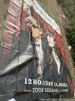 Full view of large vinyl tarp featuring illustrated man and woman promoting "12 Holiday Classics" from Zooey Deschanel and M. Ward with text and colors