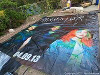 Full view of large vinyl tarp featuring Paramore band, with three members and date 04.09.13
