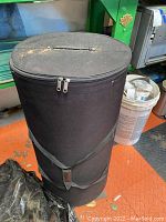 Photo of large black cylindrical display/storage bag showing top and zipper closure