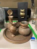 Copper serving set including tray, vessels, and lidded container next to brass owl decor