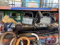Photo showing two heavy-duty work lights with protective metal guards, arranged on a workspace shelf with other tools.