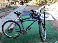 Full side view of blue Diamond Back bicycle with helmet hanging from handlebars, showing frame, wheels, seat and tires