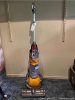 Front view showing upright vacuum with ball base and clear canister