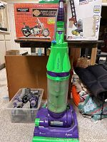 Full view of Dyson Root Cyclone vacuum upright with attachments in plastic container nearby.