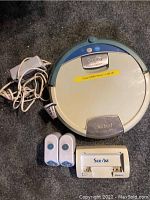 iRobot Scooba robotic vacuum with charger and two battery packs on carpet