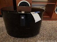 Front view of the black glossy KEF subwoofer showing its curved cabinet and KEF logo.